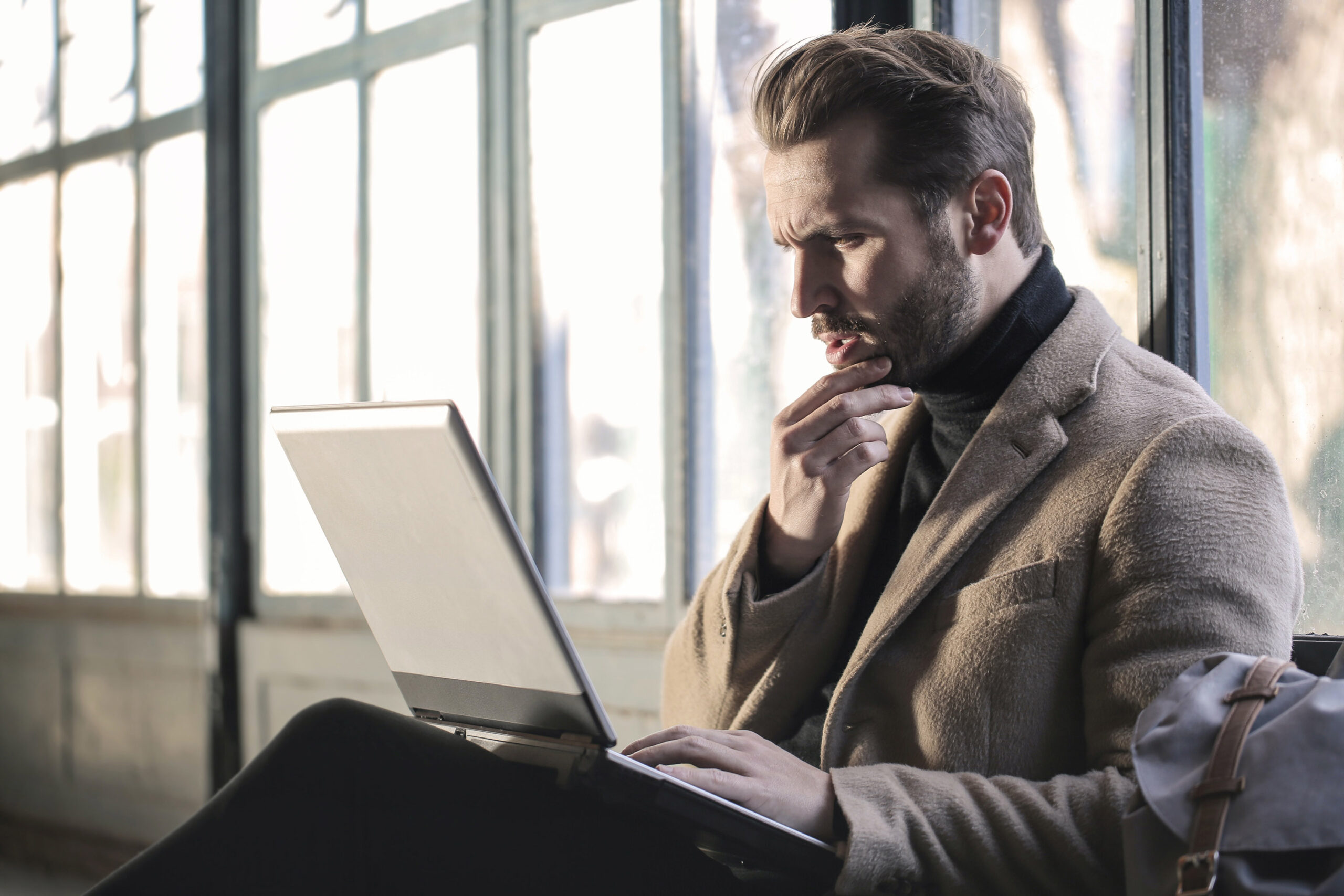 Man reading computer, considering domain usage and the benefits of having such insights.