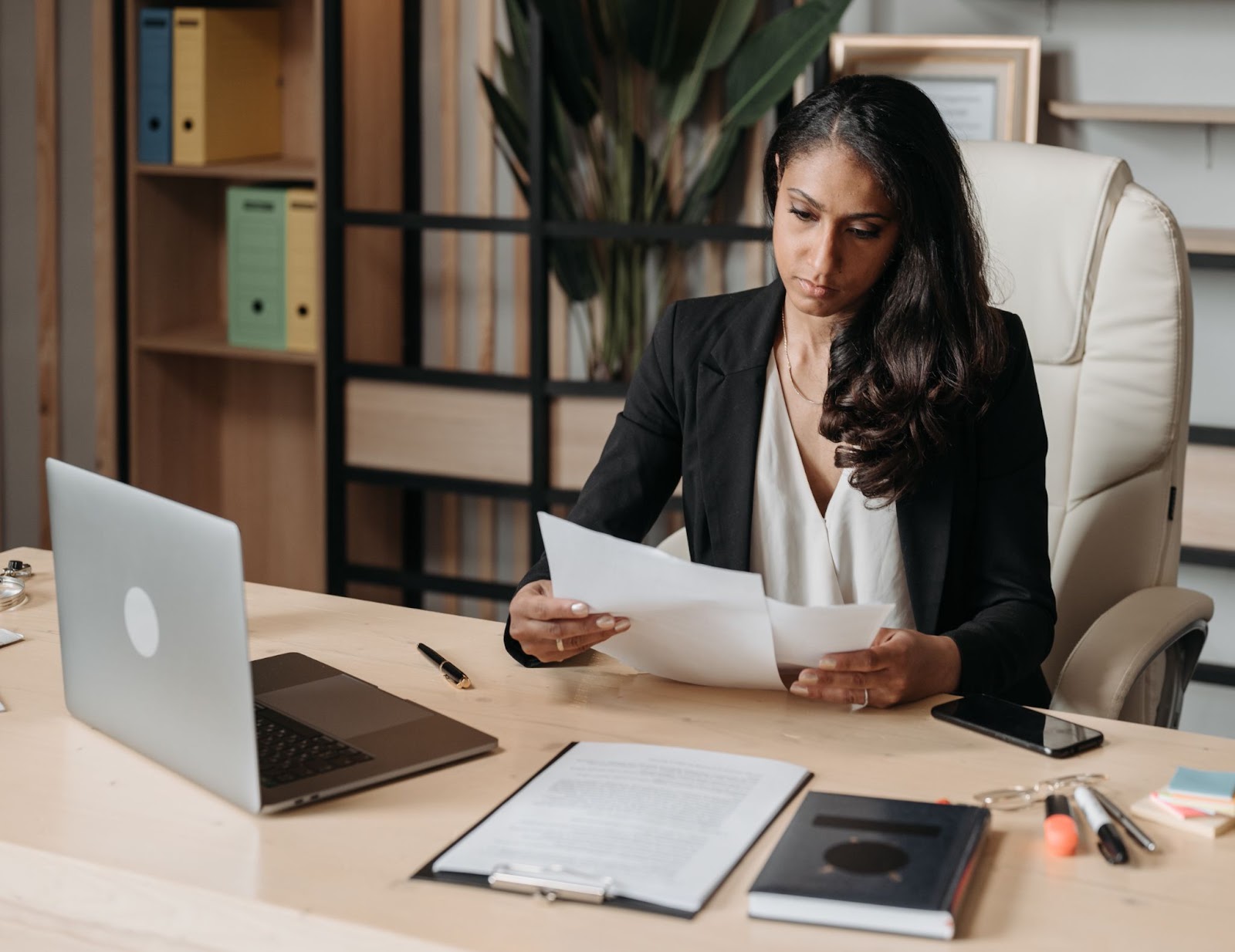 Woman at desk reviewing report papers.