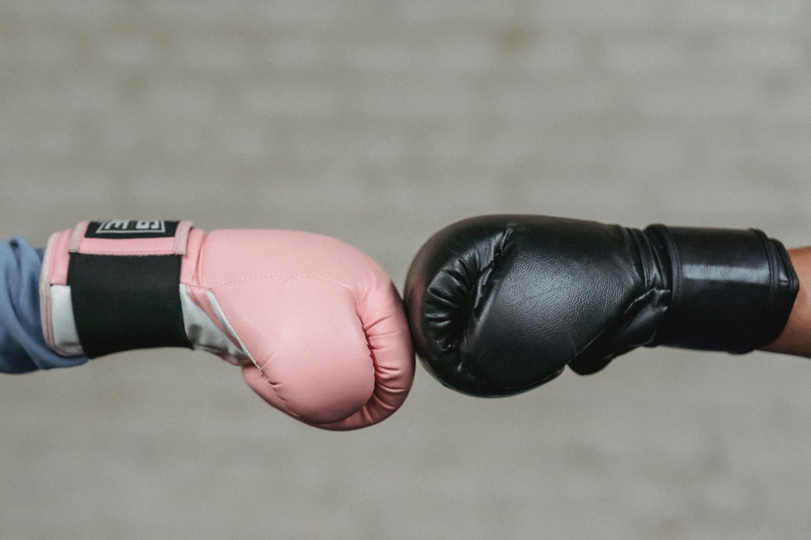 Pink and black boxing gloves touching